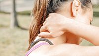 A woman holding the back of her neck with one hand