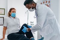 A clinician examining the leg of a seated patient